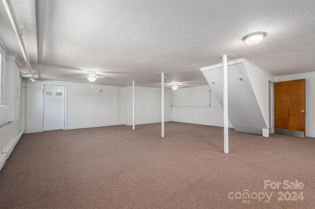 basement featuring ceiling fan, carpet, and a textured ceiling