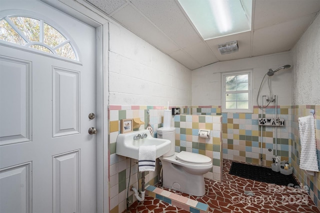 bathroom featuring a tile shower, vaulted ceiling, toilet, and tile walls