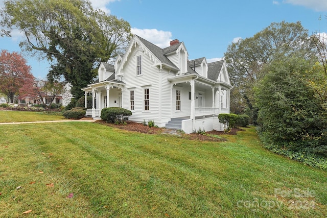 view of side of property featuring covered porch and a yard