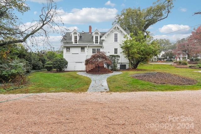 rear view of house with a yard, central AC unit, and a garage