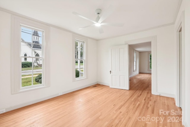 empty room with plenty of natural light, ceiling fan, and light wood-type flooring