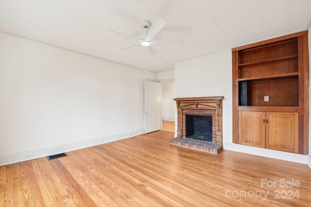 unfurnished living room with hardwood / wood-style floors, ceiling fan, and a brick fireplace