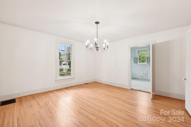 unfurnished room featuring hardwood / wood-style floors and a notable chandelier