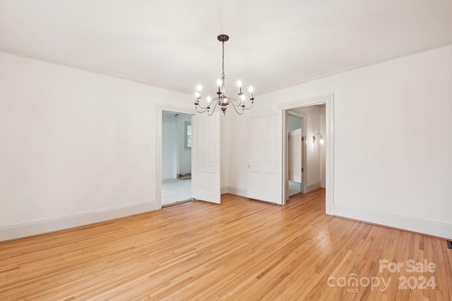 empty room with a notable chandelier and wood-type flooring