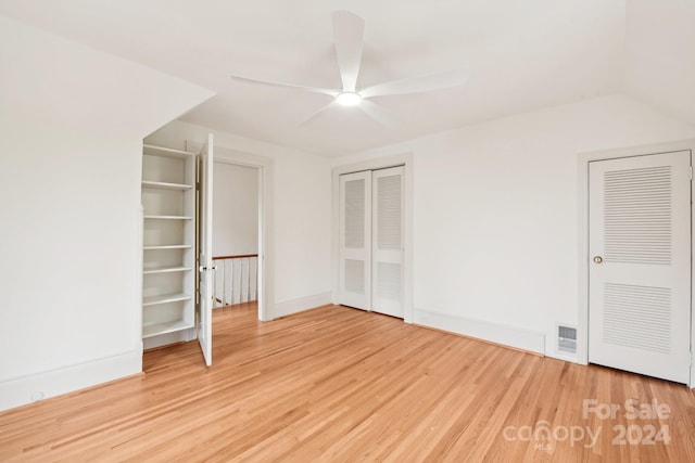 unfurnished bedroom with hardwood / wood-style floors, ceiling fan, and multiple closets