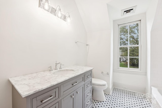 bathroom with tile patterned floors, vanity, toilet, and lofted ceiling