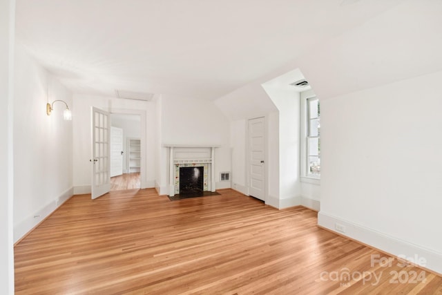 unfurnished living room with light wood-type flooring and a tile fireplace