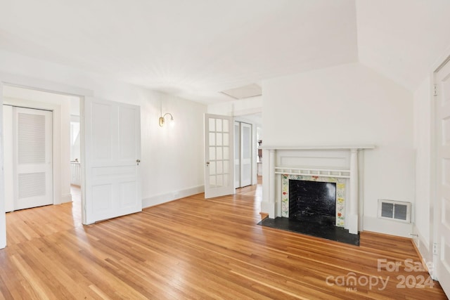 unfurnished living room with vaulted ceiling, a healthy amount of sunlight, and light hardwood / wood-style flooring