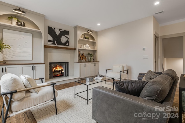 living room featuring built in features and light hardwood / wood-style floors