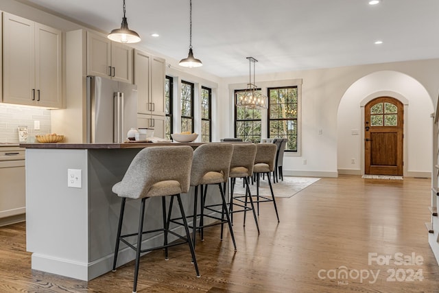 kitchen with a kitchen breakfast bar, high end fridge, and light hardwood / wood-style floors