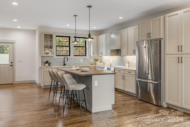 kitchen featuring premium range hood, high end fridge, a center island, and a healthy amount of sunlight