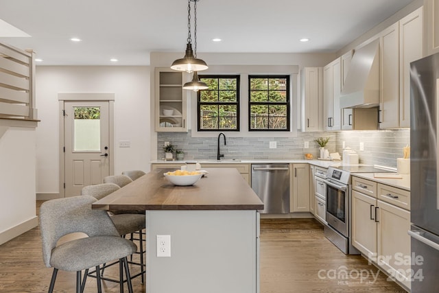 kitchen featuring custom range hood, stainless steel appliances, hardwood / wood-style flooring, a center island, and a breakfast bar area