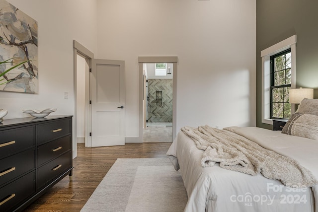 bedroom with a high ceiling, dark hardwood / wood-style flooring, and ensuite bath