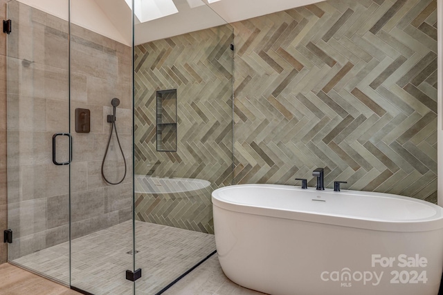 bathroom featuring shower with separate bathtub, parquet floors, tile walls, and a skylight