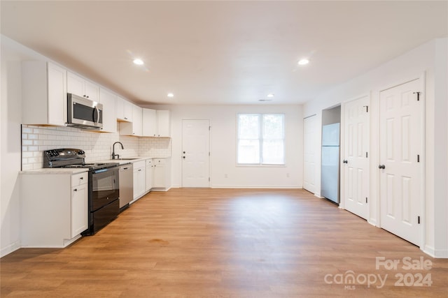 kitchen with stainless steel appliances, white cabinetry, light hardwood / wood-style floors, and sink