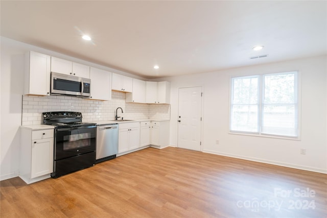 kitchen with white cabinetry, sink, stainless steel appliances, backsplash, and light wood-type flooring