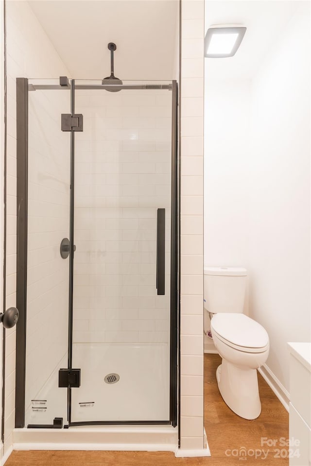 bathroom with wood-type flooring, an enclosed shower, and toilet