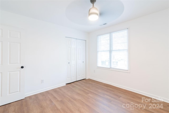 unfurnished bedroom with a closet, light hardwood / wood-style flooring, and ceiling fan