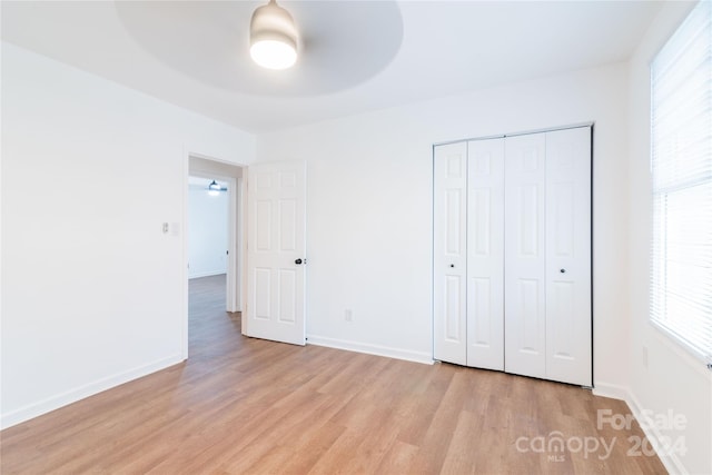 unfurnished bedroom featuring ceiling fan, light wood-type flooring, and a closet