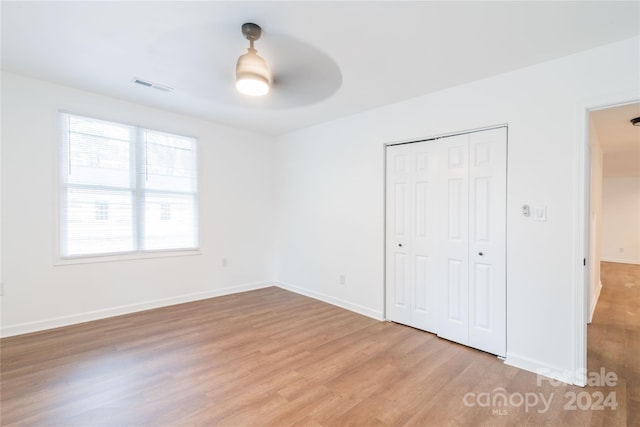 unfurnished bedroom featuring ceiling fan, light hardwood / wood-style floors, and a closet