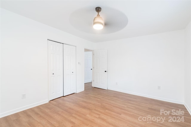 unfurnished bedroom with ceiling fan, light wood-type flooring, and a closet