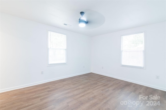 empty room with ceiling fan, a healthy amount of sunlight, and light hardwood / wood-style floors