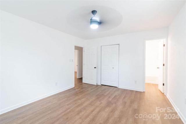 unfurnished bedroom featuring a closet, light hardwood / wood-style floors, and ceiling fan