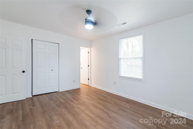 unfurnished bedroom featuring a closet, hardwood / wood-style flooring, and ceiling fan