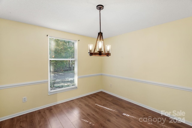 spare room featuring wood-type flooring and a notable chandelier