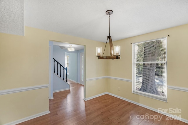 unfurnished dining area featuring hardwood / wood-style floors and a notable chandelier