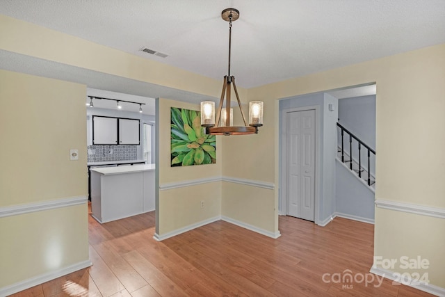 unfurnished dining area featuring a chandelier and light hardwood / wood-style floors