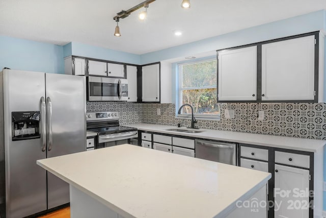 kitchen featuring tasteful backsplash, stainless steel appliances, sink, a center island, and light hardwood / wood-style floors