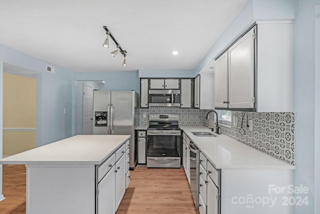 kitchen with backsplash, sink, light wood-type flooring, and stainless steel appliances