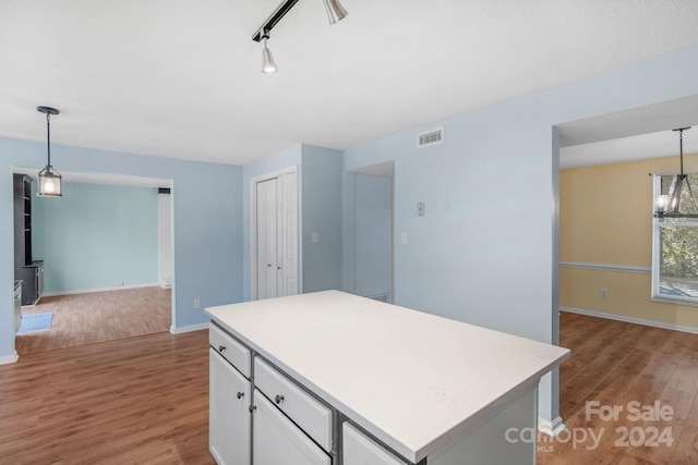 kitchen with light wood-type flooring, pendant lighting, a chandelier, a center island, and white cabinetry