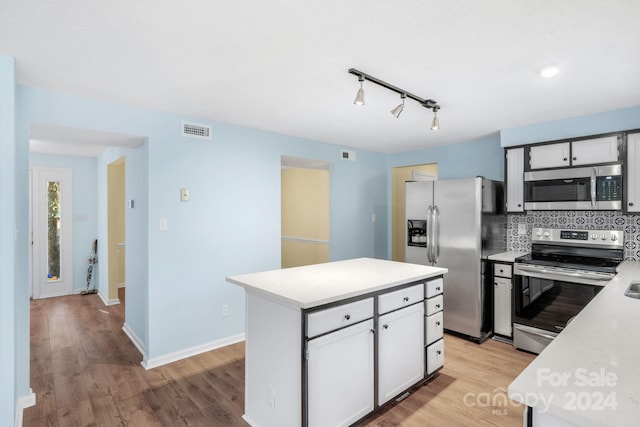 kitchen with white cabinetry, stainless steel appliances, tasteful backsplash, light hardwood / wood-style floors, and a kitchen island