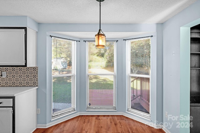 doorway to outside with a textured ceiling and light hardwood / wood-style flooring