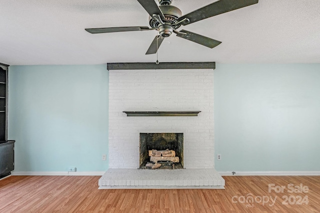 unfurnished living room with ceiling fan, hardwood / wood-style floors, a textured ceiling, and a brick fireplace