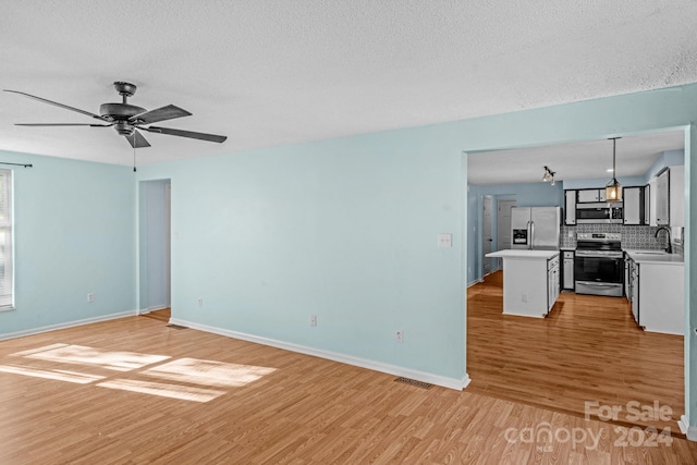 interior space with a textured ceiling, light hardwood / wood-style flooring, ceiling fan, and sink