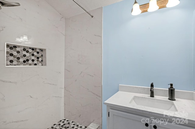 bathroom with tiled shower and vanity