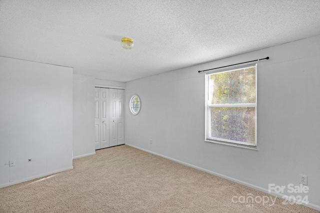 spare room featuring light carpet and a textured ceiling