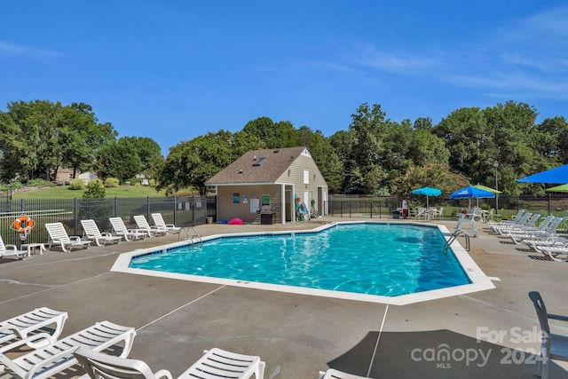 view of swimming pool featuring a patio and an outdoor structure