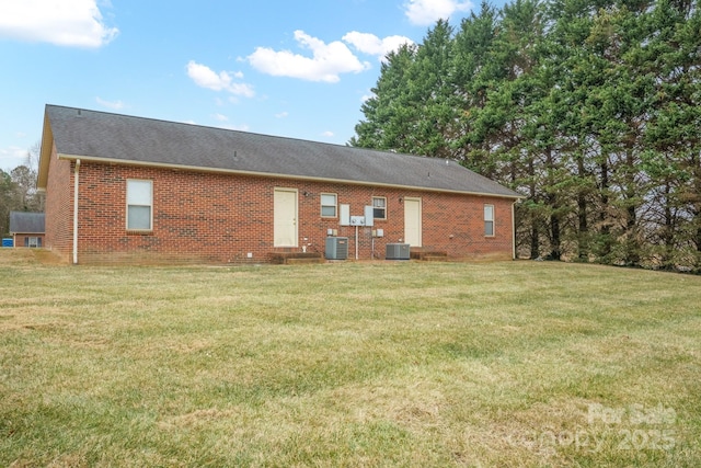 rear view of property featuring a yard, brick siding, and central AC unit