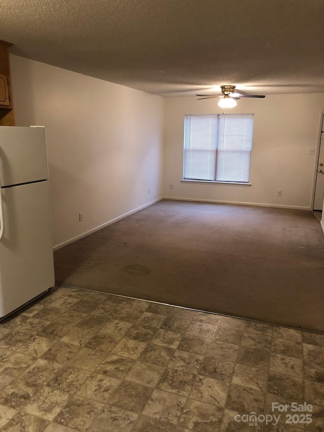 unfurnished room with ceiling fan, dark colored carpet, a textured ceiling, and baseboards