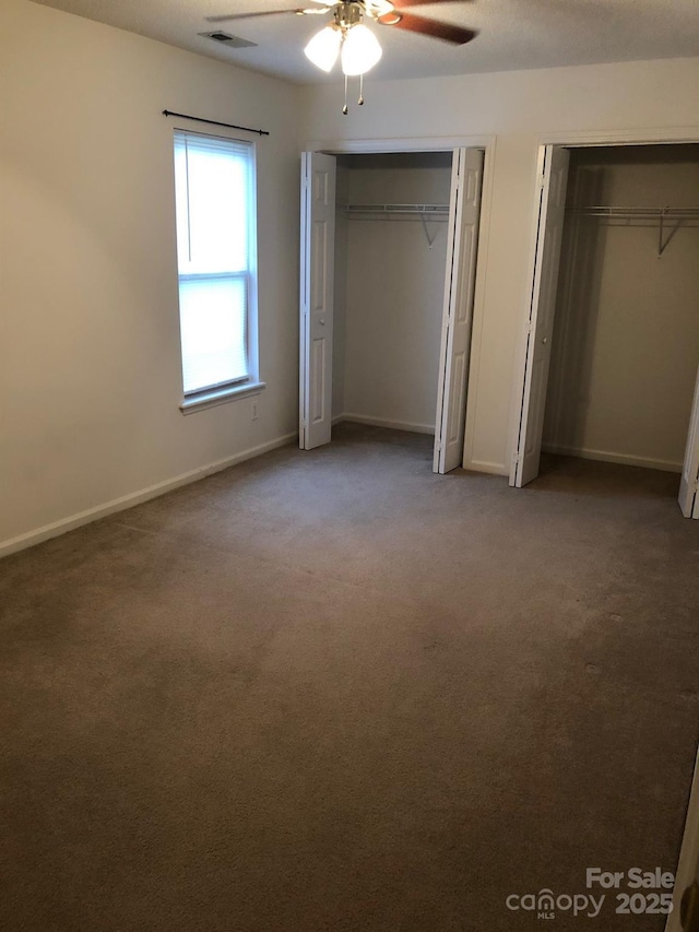 unfurnished bedroom with multiple closets, baseboards, visible vents, and carpet flooring