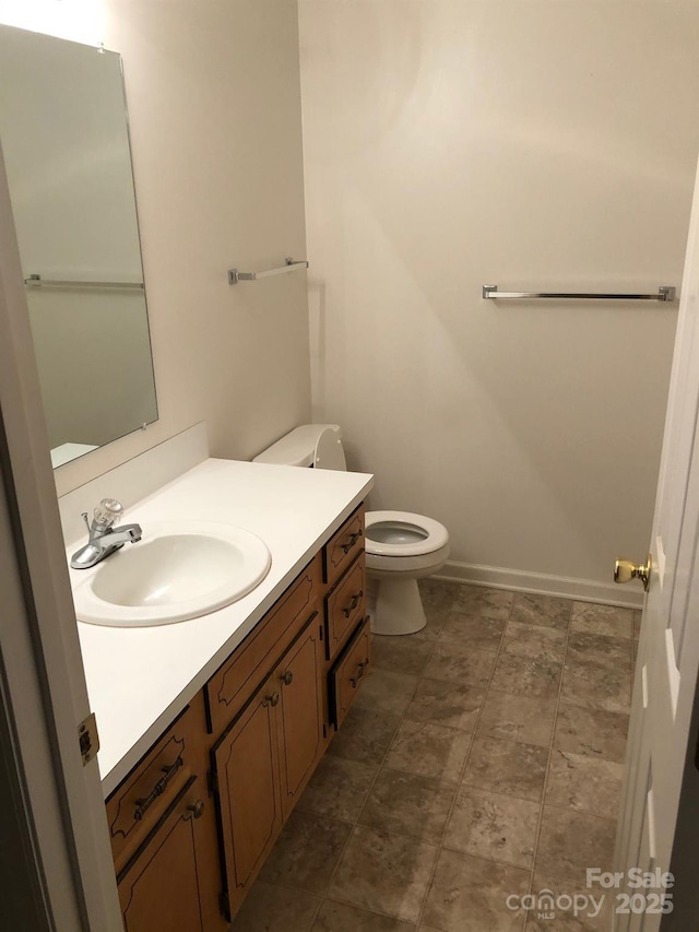 bathroom featuring toilet, baseboards, and vanity