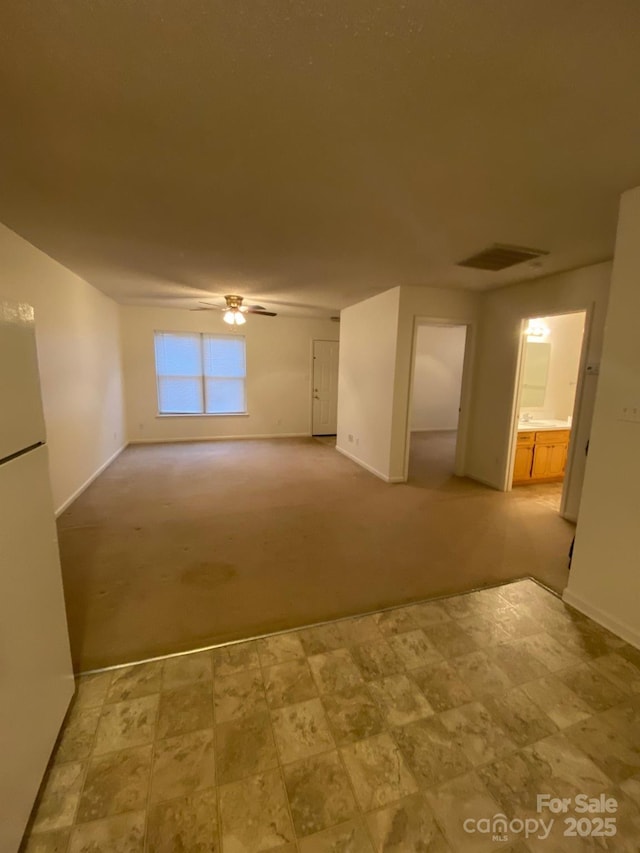 carpeted empty room with baseboards, visible vents, and a ceiling fan