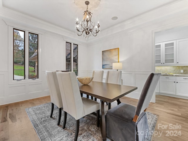 dining area featuring light hardwood / wood-style flooring, a chandelier, and ornamental molding