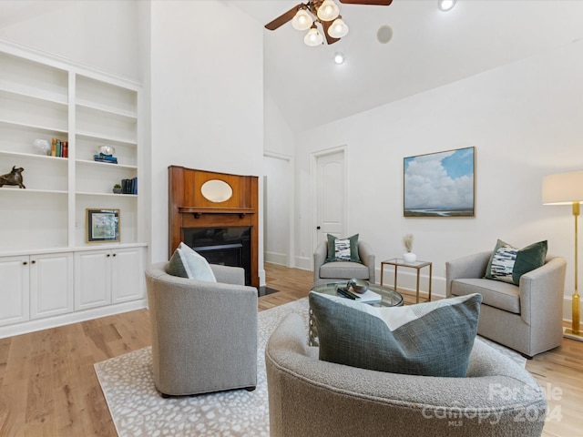 living room with light wood-type flooring, high vaulted ceiling, and ceiling fan