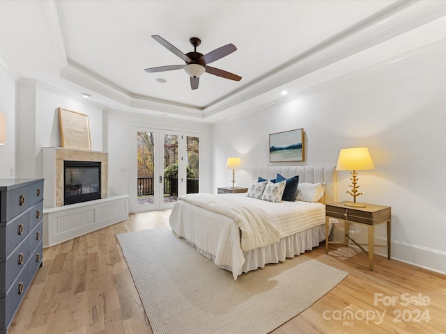 bedroom with a raised ceiling, ceiling fan, access to exterior, and light hardwood / wood-style flooring