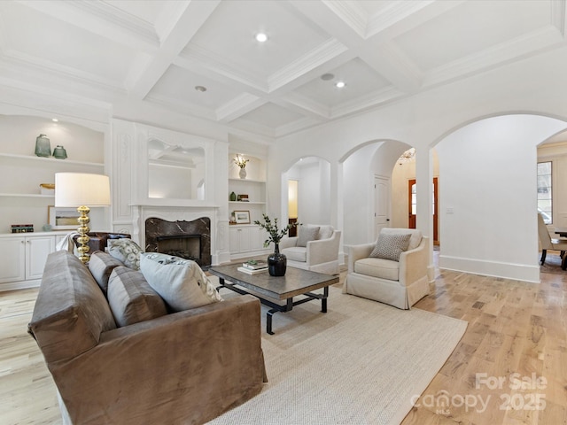 living room with beamed ceiling, a high end fireplace, light wood-type flooring, and built in shelves